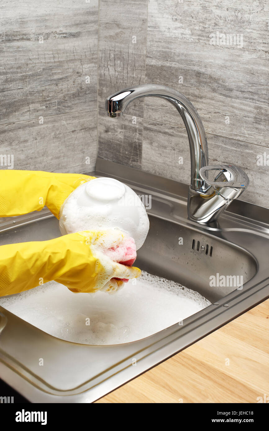 Close up of female hands in yellow protective rubber gloves washing ...
