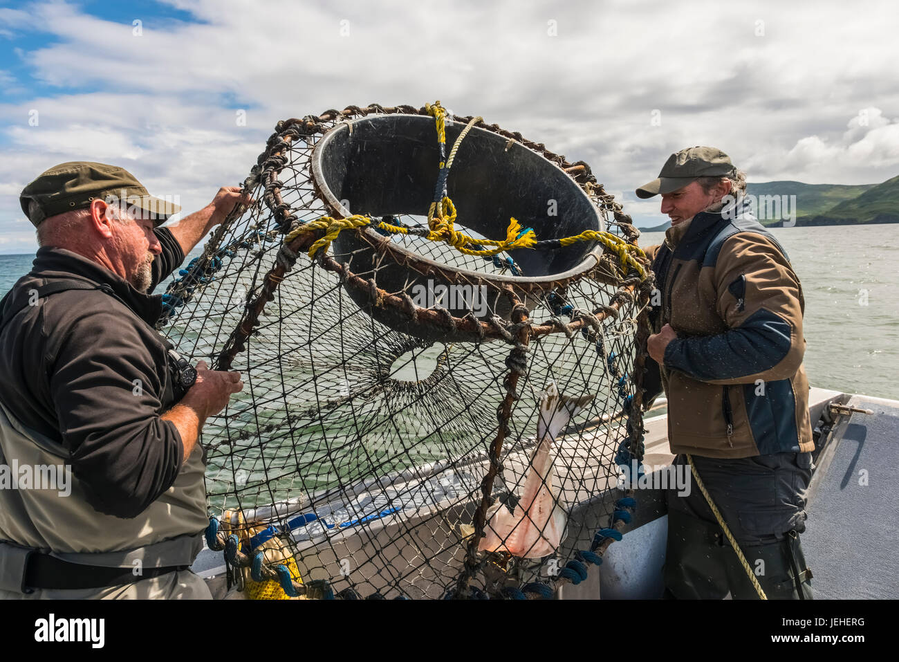 Two men prepare to drop a crab pot baited with halibut in the Cook Inlet near Kukak Bay, Katmai National Park & Preserve, Southwest Alaska, USA Stock Photo