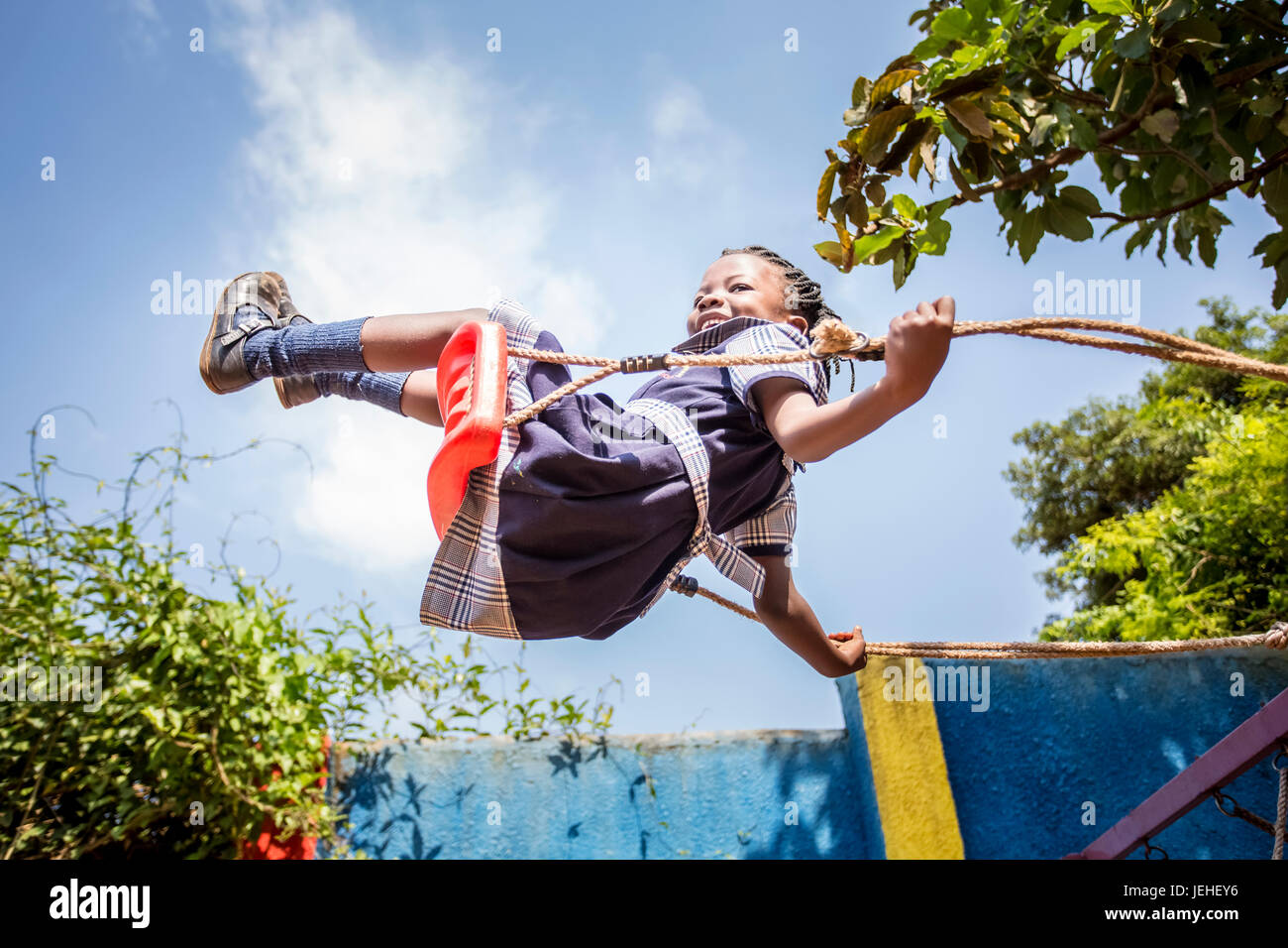 A young girl swinging on a swing in mid-air; Kampala, Uganda Stock Photo