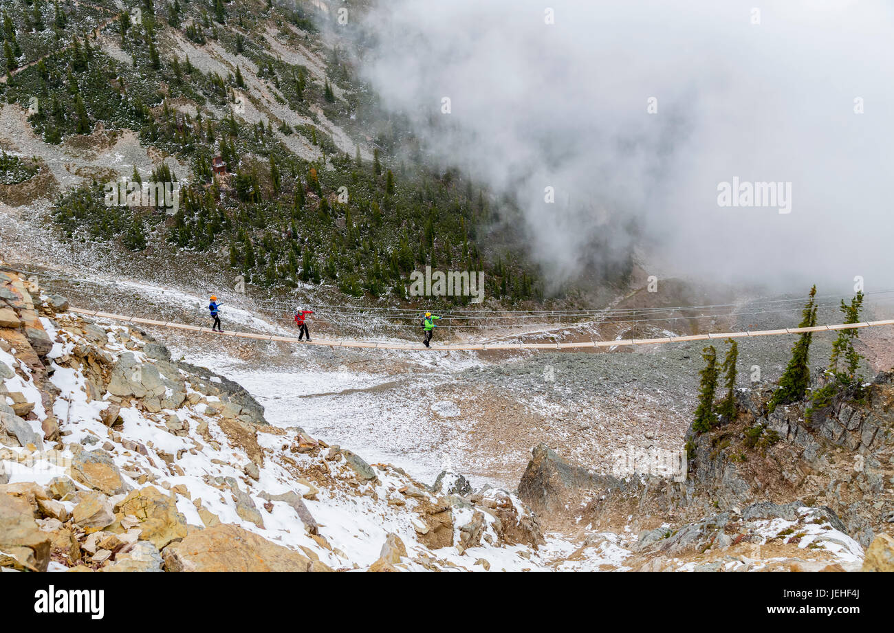 A group of rock climbers walk across the suspension bridge at Kicking