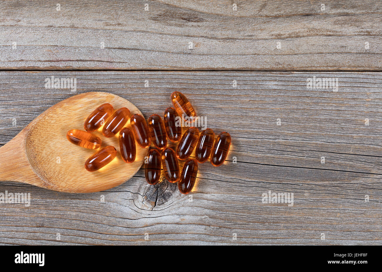 Pacific salmon fish oil capsules and wooden spoon on rustic wood. Flat lay view. Stock Photo
