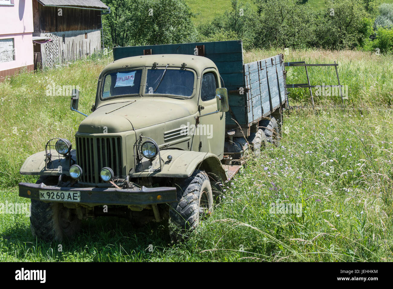 An old truck of the Soviet era in a meadow at the edge of a street in Ukraine Stock Photo