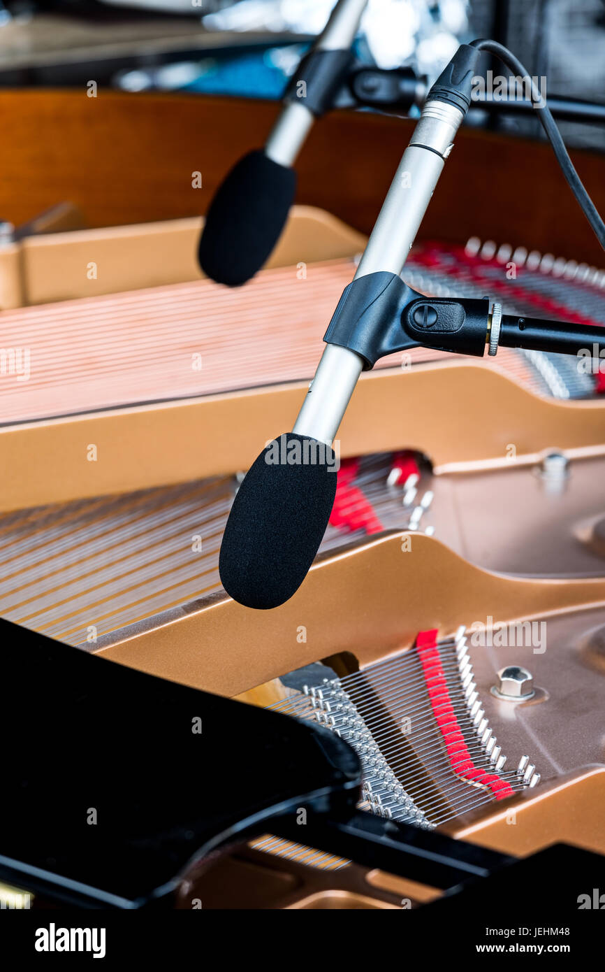 professional microphones above grand piano with selective focus on one of them Stock Photo