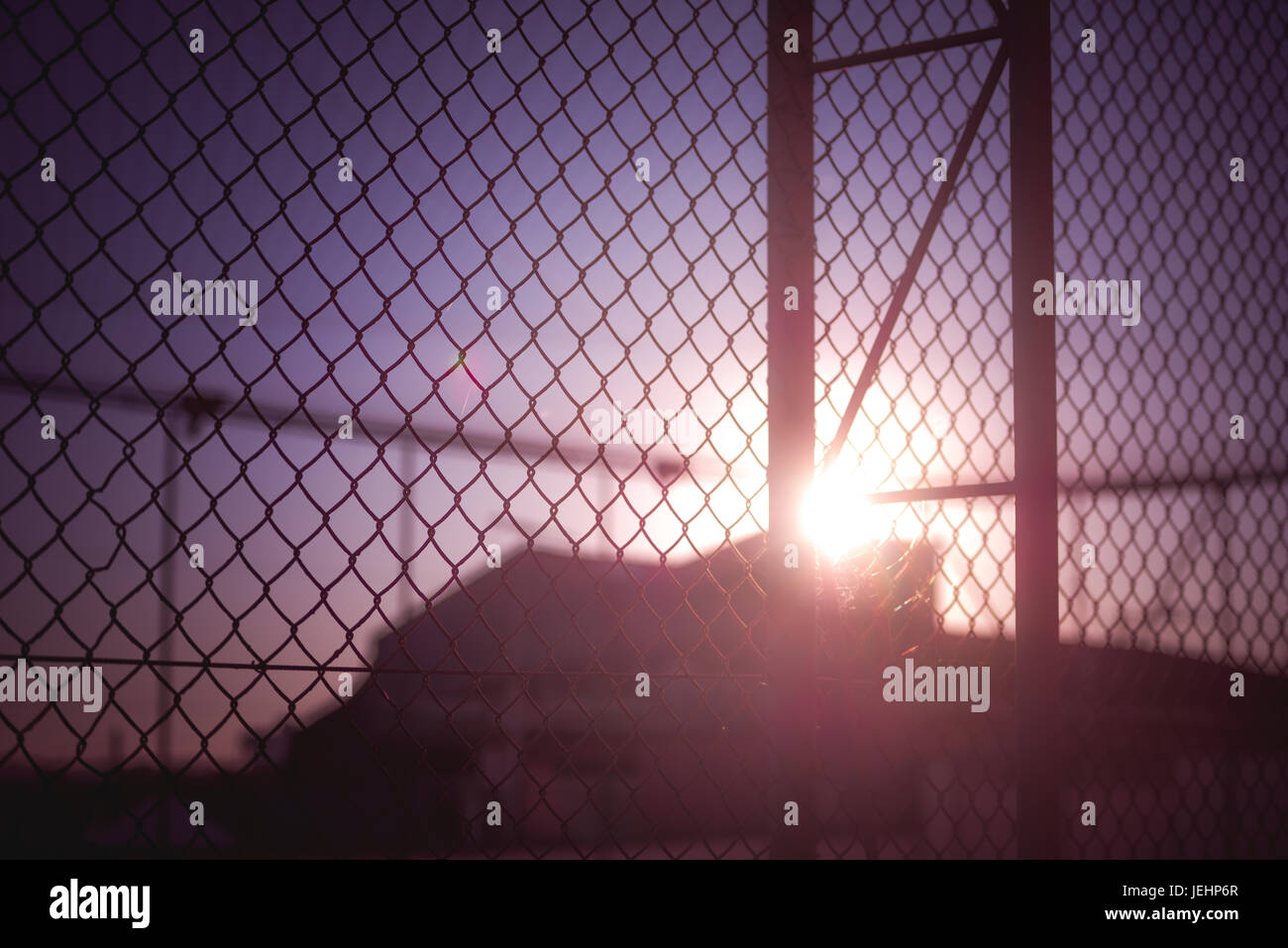 Sunset behind a rusty wire fence. Stock Photo