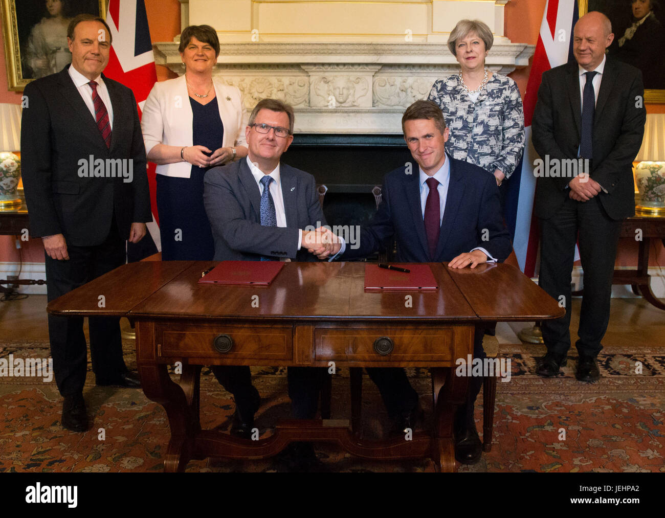 Prime Minister Theresa May stands with First Secretary of State Damian Green (right), DUP leader Arlene Foster (second left), DUP Deputy Leader Nigel Dodds (left), as DUP MP Sir Jeffrey Donaldson (third right) shakes hands with Parliamentary Secretary to the Treasury, and Chief Whip, Gavin Williamson, inside 10 Downing Street, London, after the DUP agreed a deal to support the minority Conservative government. Stock Photo