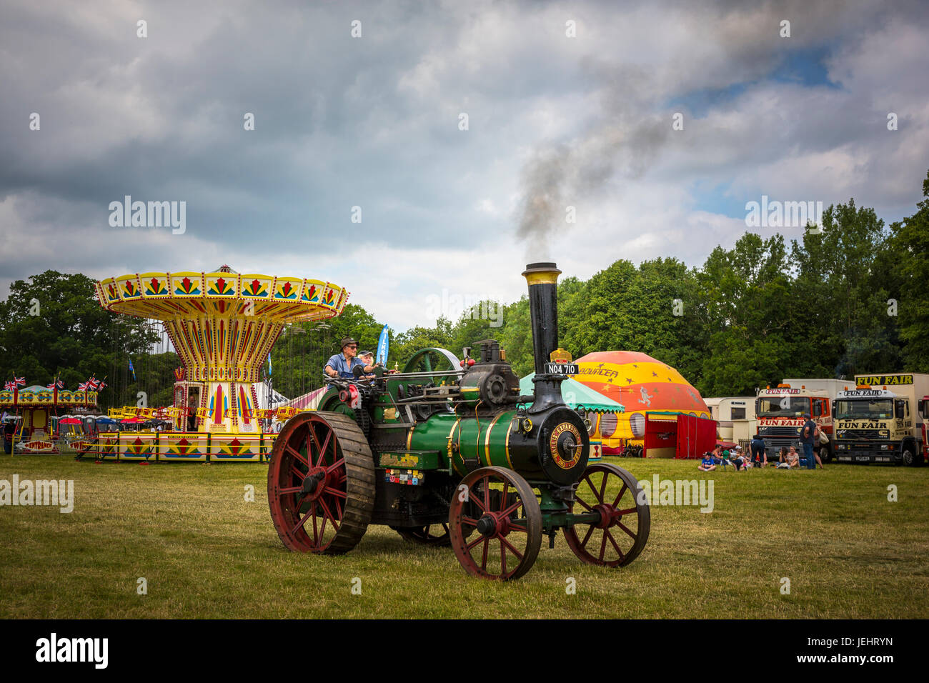 A steam engine at a steam engine rally slowly passes a funfair in Norfolk. Stock Photo