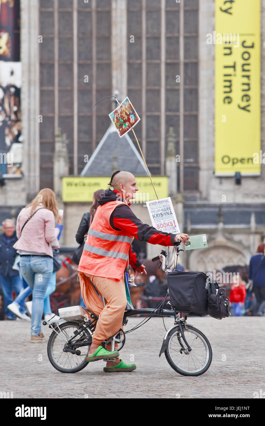 AMSTERDAM-AUG. 26, 2014. Hare Krishna on fold-able bicycle at Dam Square. Hare Krishna is a religious movement based on traditional Hindu scriptures. Stock Photo