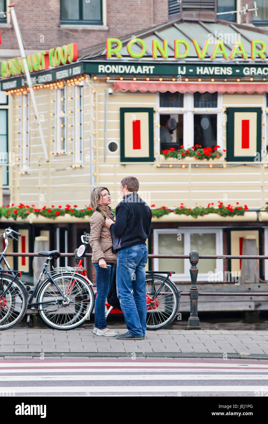 AMSTERDAM-AUGUST 26, 2014. Couple having romantic time near tour-boat starting point. Its historic canal belt with lovely ancient houses and canals. Stock Photo