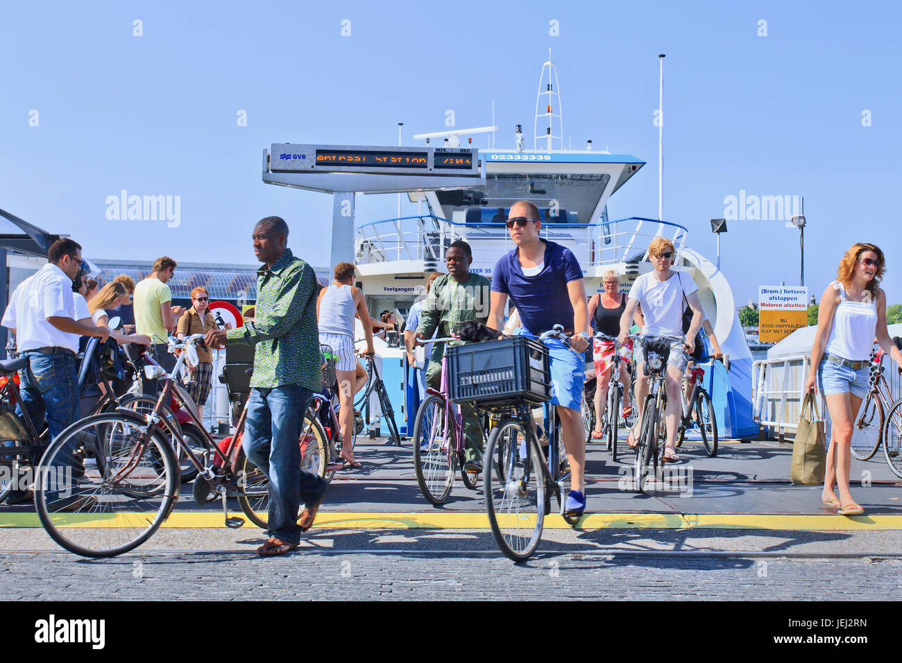 AMSTERDAM-AUG. 19, 2012. Cyclists and pedestrians on ferryboat arrival. With 175 different nationalities is Amsterdam world's most multicultural city. Stock Photo