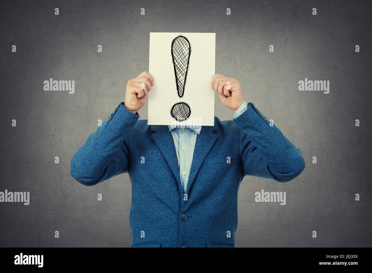 Businessman covering his face using a paper  with a exclamation mark Stock Photo