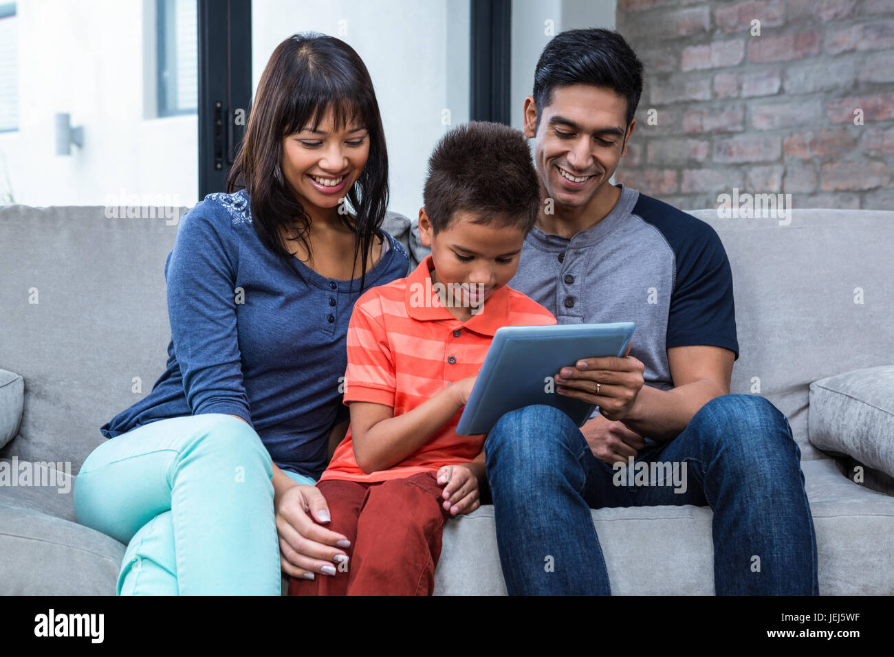 Smiling family using tablet on the sofa Stock Photo - Alamy