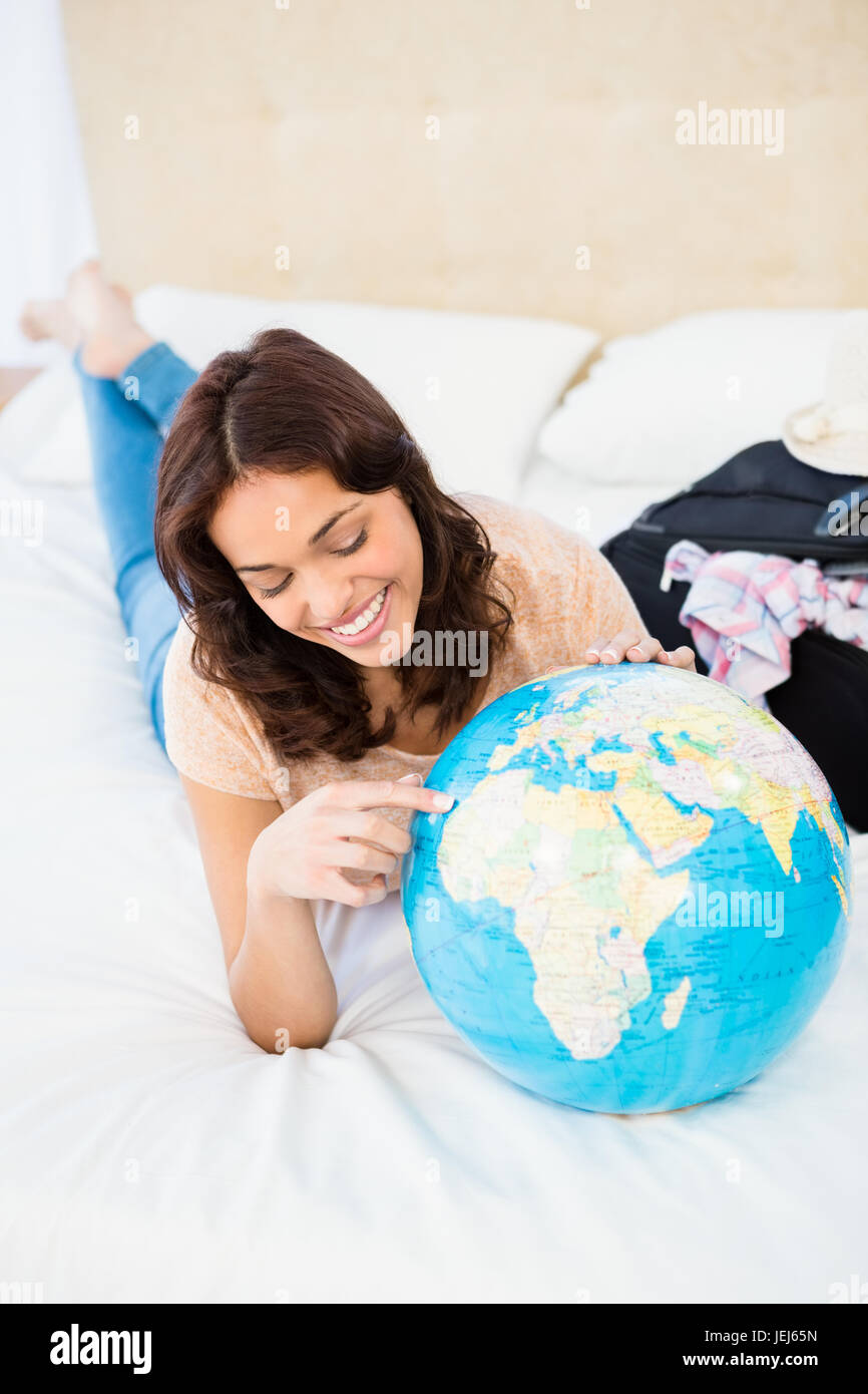 Smiling woman lying on bed while holding a globe Stock Photo - Alamy