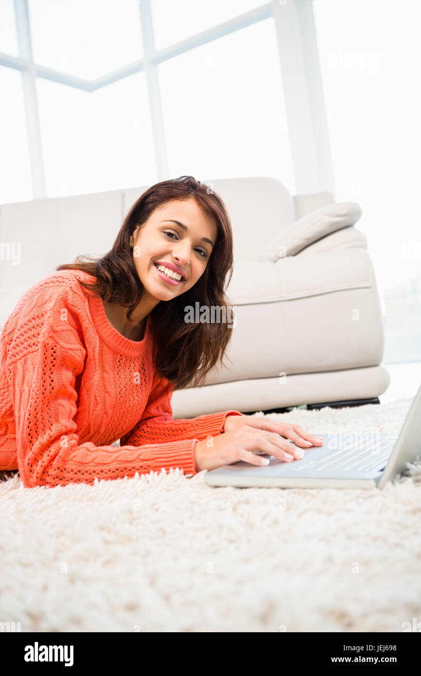 Smiling woman using laptop while lying on the floor Stock Photo - Alamy