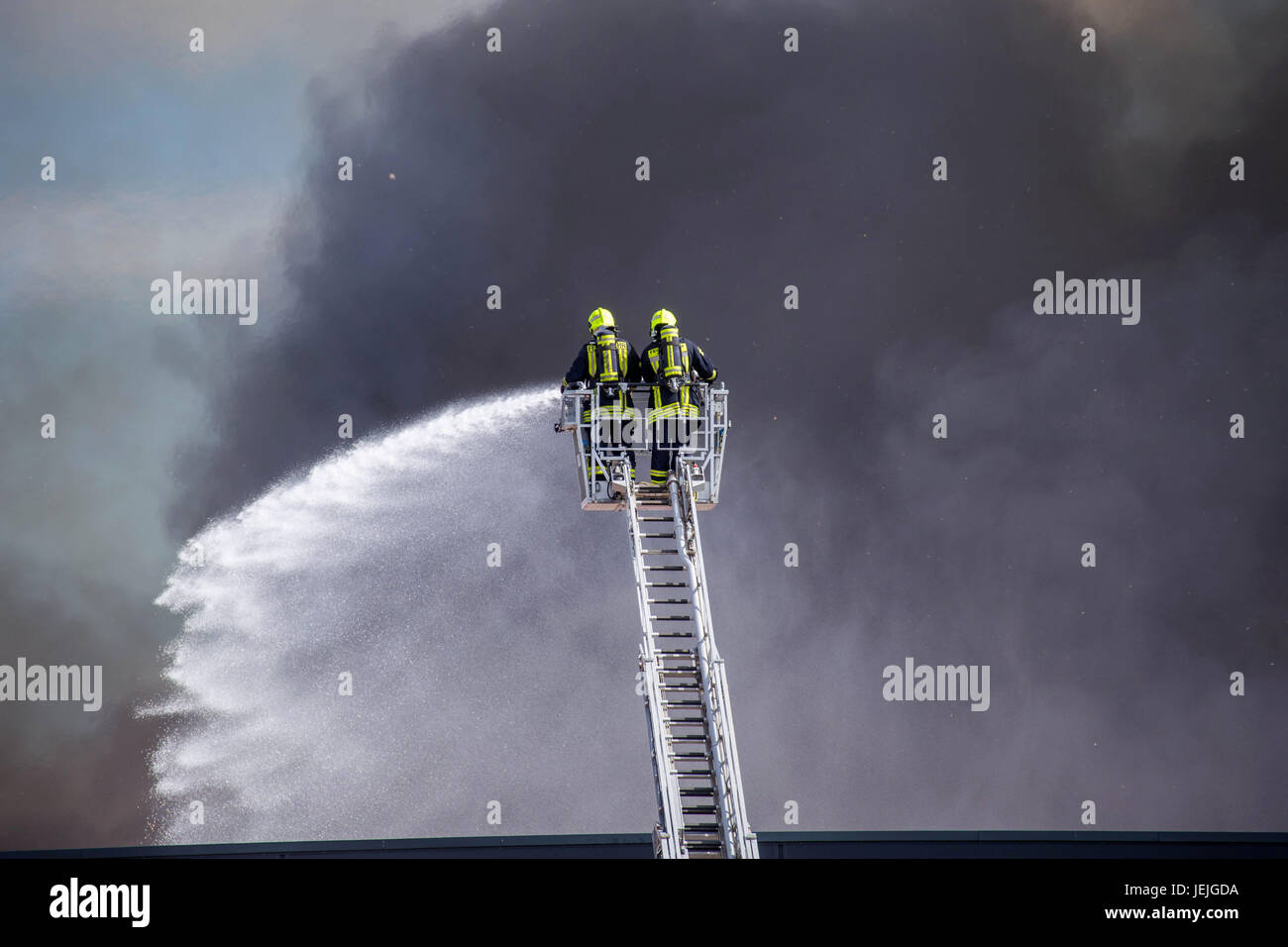 Fire fighters on a ladder fight against the flames inside a furniture manufactury in Elterlein, Germany, 25 June 2017. Photo: Andre März/dpa Stock Photo