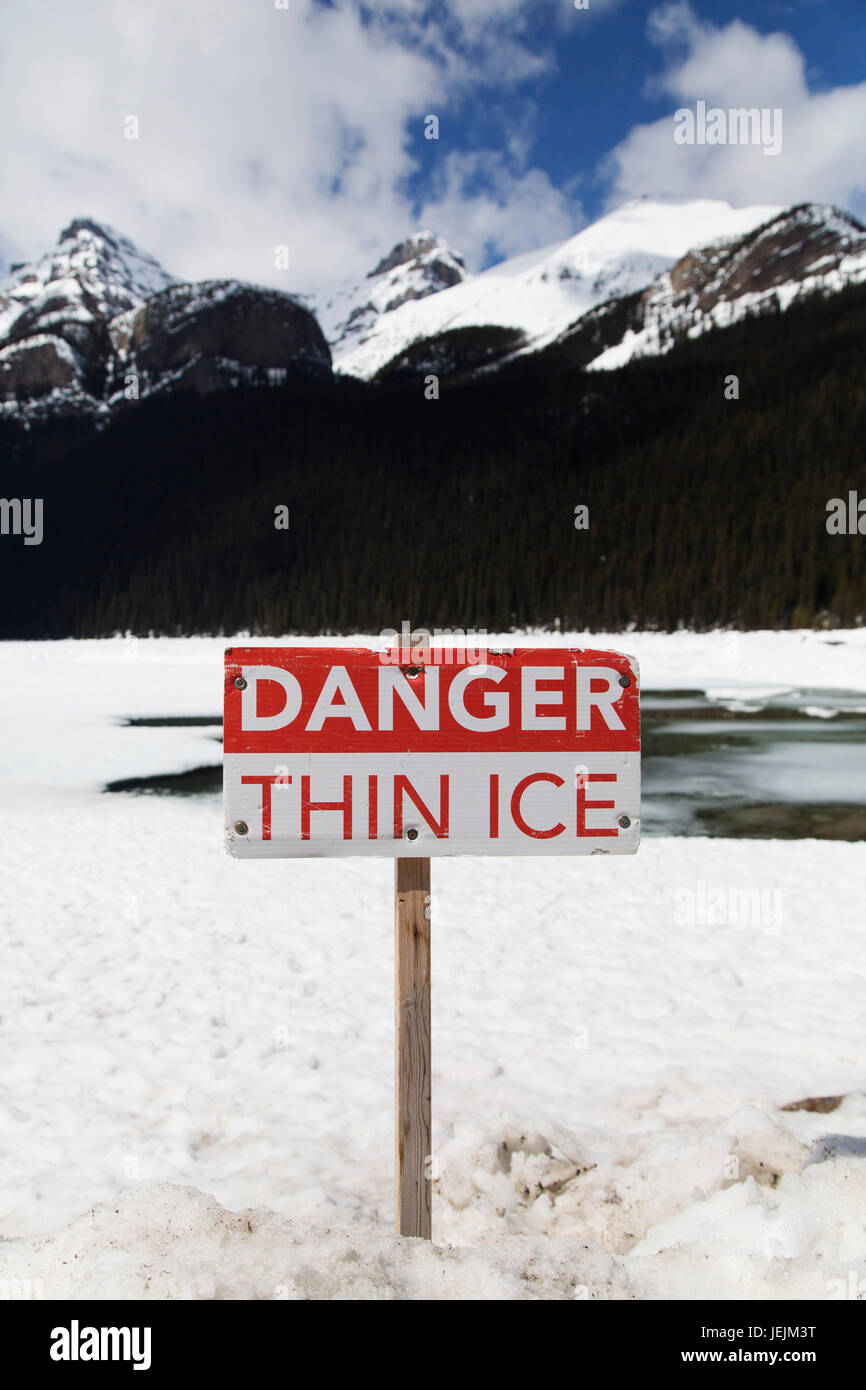 Sign warning of the danger posed by thin ice on Lake Louise in Alberta, Canada. The area around the lake is one of Canada's most popular ski resorts. Stock Photo