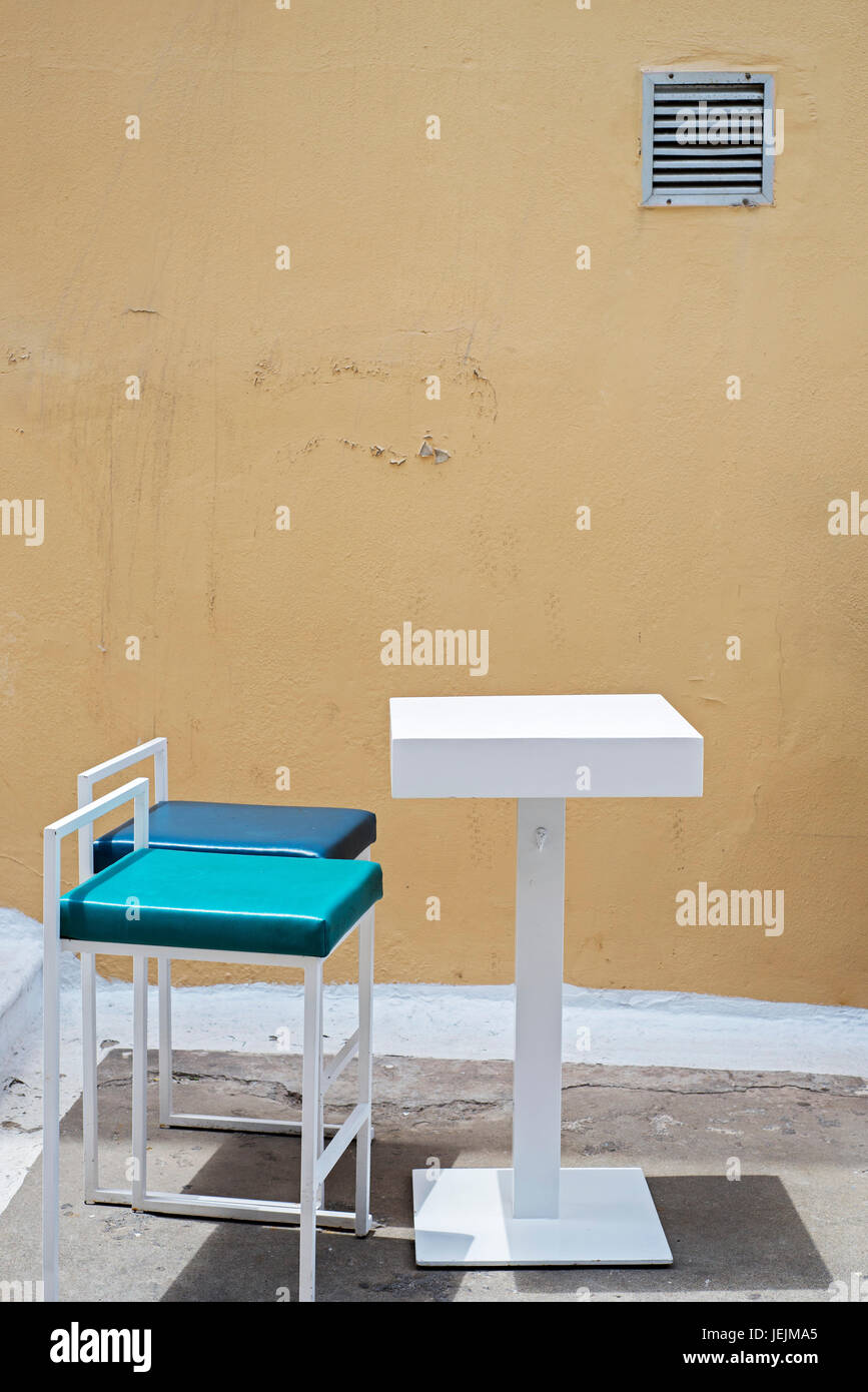 outdoor table and two chairs near the grunge wall Stock Photo