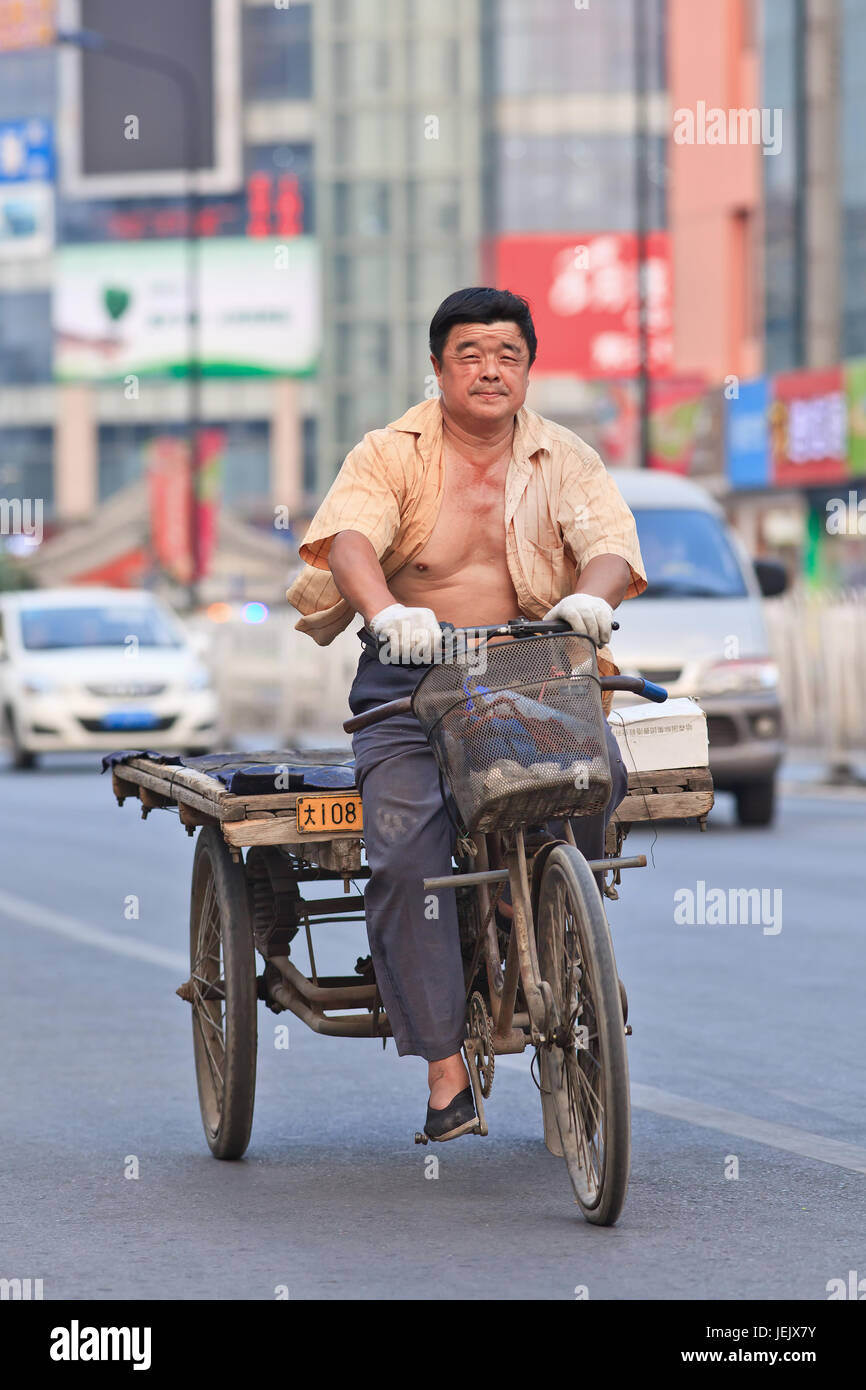BEIJING-JULY 10, 2015. Man on rusty freight bike. Although municipal governments try to ban them out this transportation mode is still convenient. Stock Photo