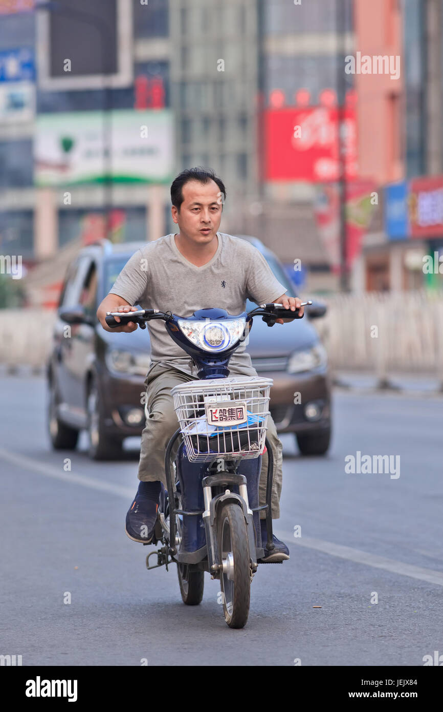 BEIJING-JULY 10, 2015. Man on an e-bike. In a decade, e-bikes in China climbed from near zero to over 150 million by 2015. Stock Photo