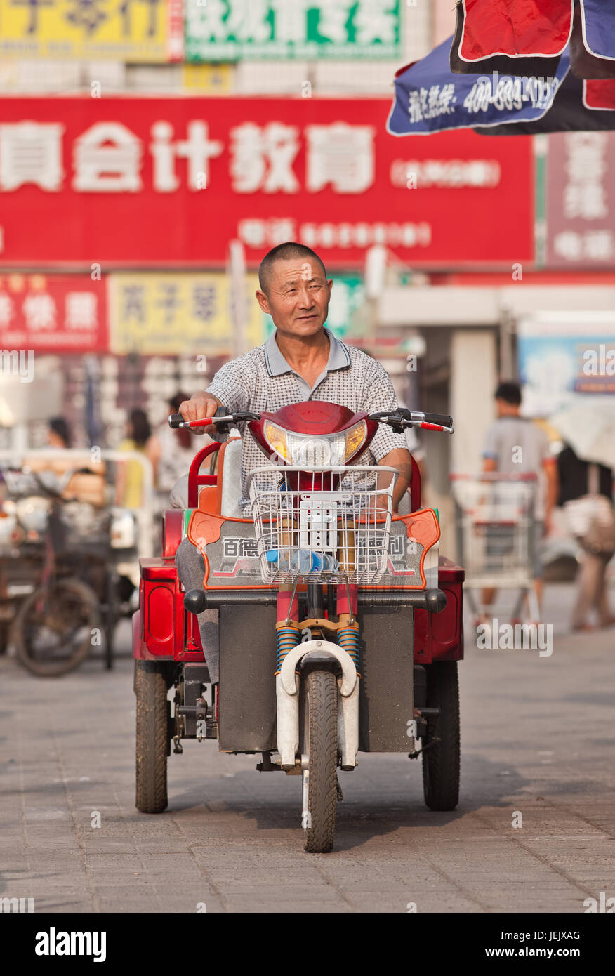 BEIJING-JULY 24, 2015. Elderly on electric trike. In a decade, e-bikes in China climbed from near zero to 150 million (2015). Stock Photo