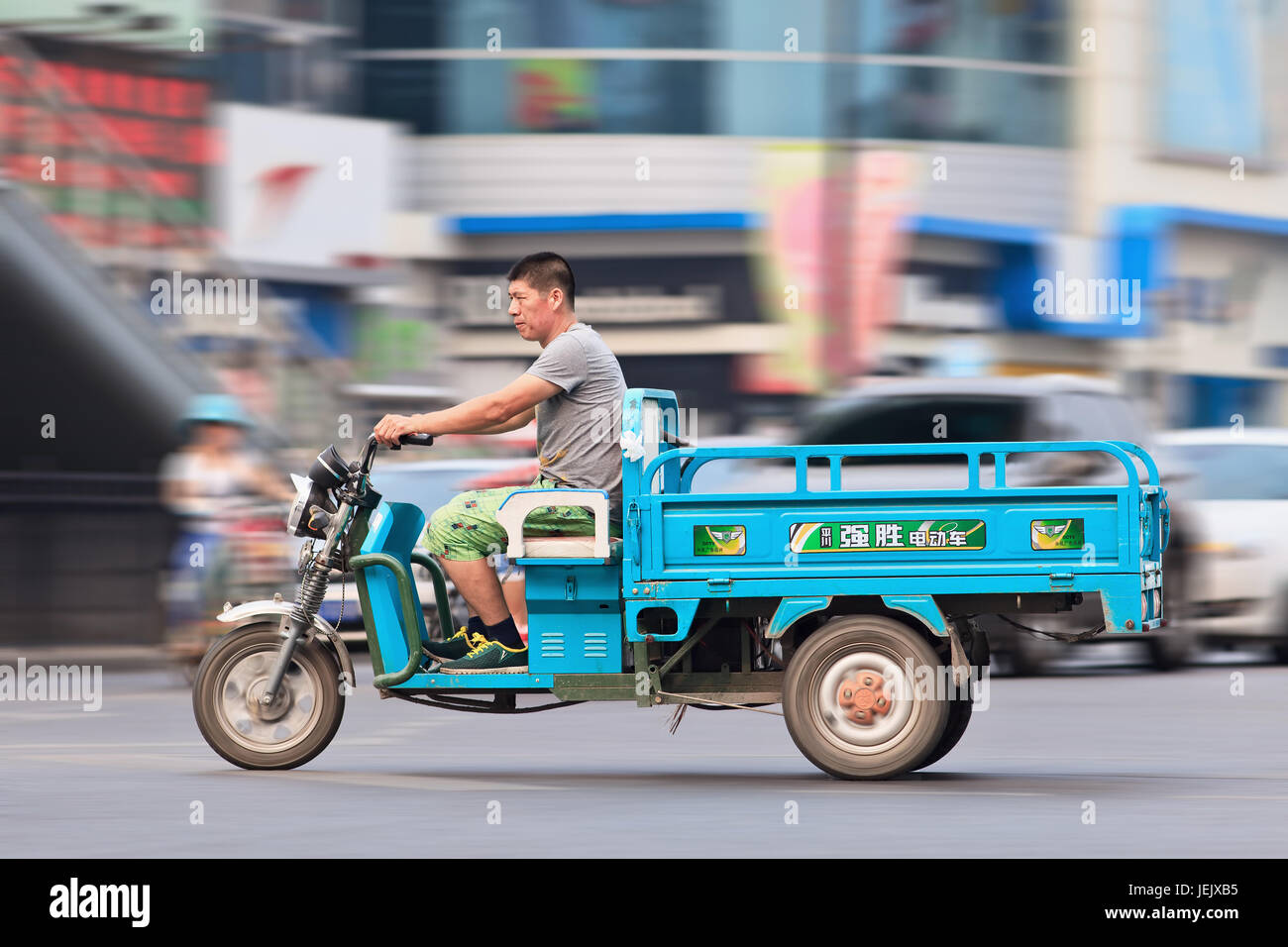 BEIJING-JULY 27, 2015. Man on electric freight tricycle in Beijing downtown. The police in major Chinese cities crackdown on unlicensed electric bikes. Stock Photo