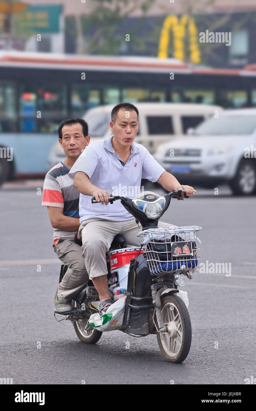 BEIJING-JULY 27, 2015. Men on electric powered bike transport paint can. Stock Photo