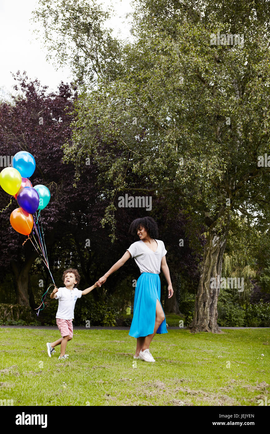 Mother with son walking with bunch of balloons Stock Photo