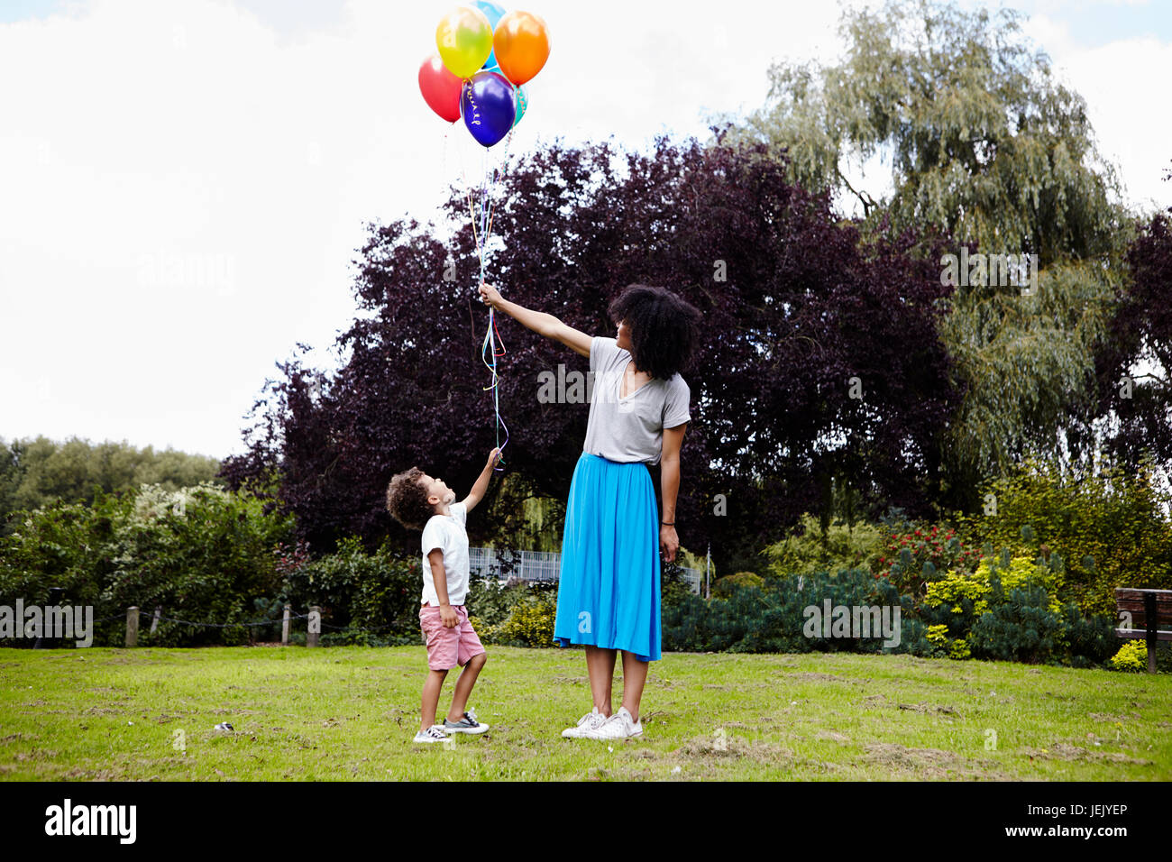 Mother with son holding bunch of balloons Stock Photo
