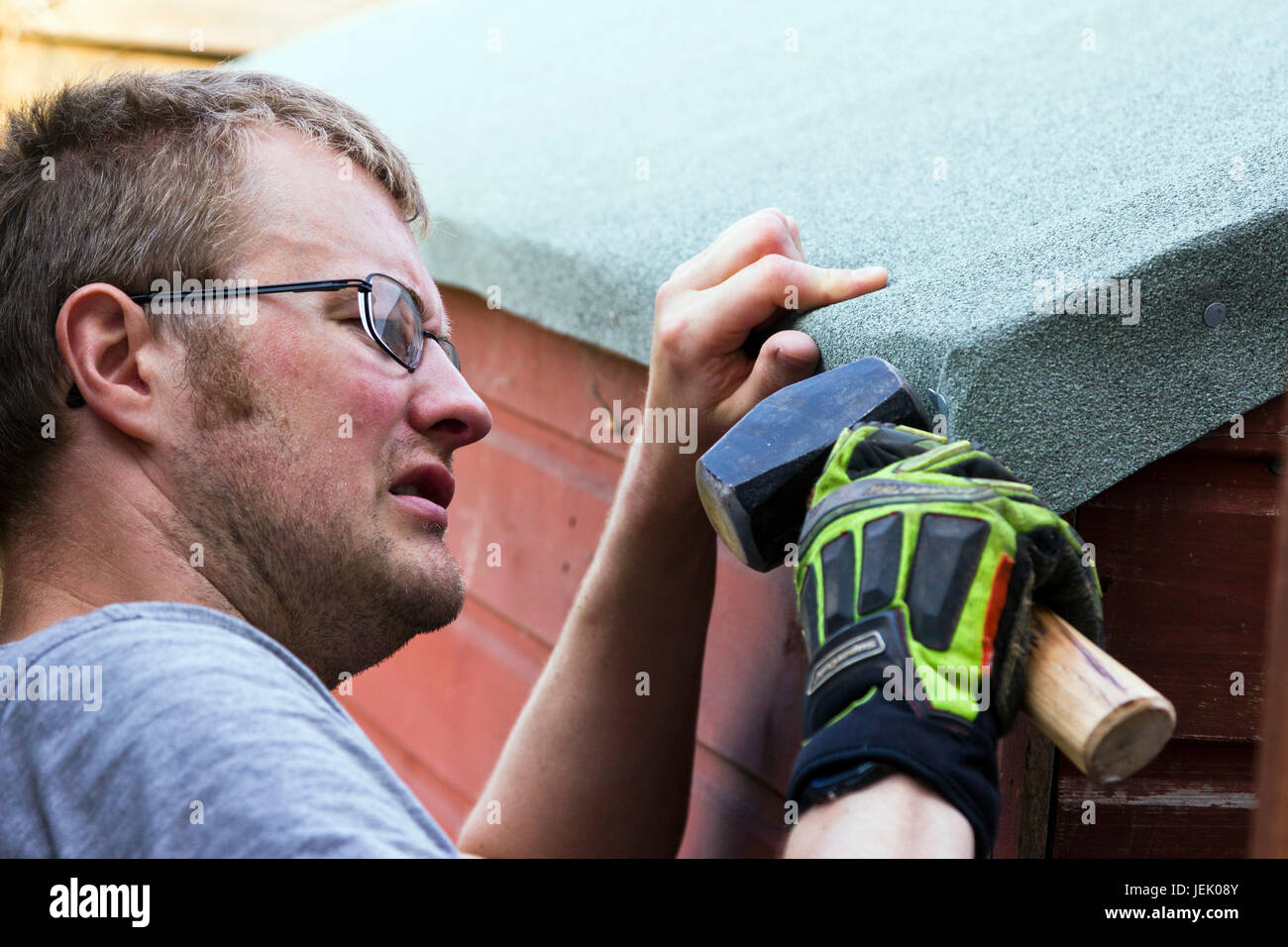 Man felting the roof of a garden shed Stock Photo