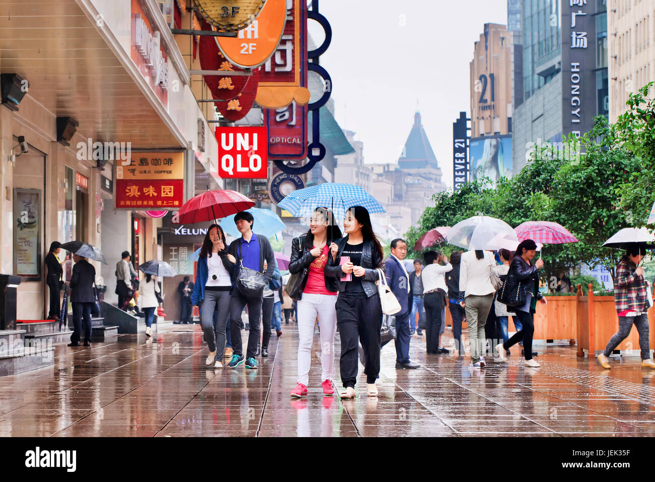 Shoppers with umbrella in wet Nanjing East Road. Shanghai has a humid subtropical climate, its summer is very warm and humid. Stock Photo