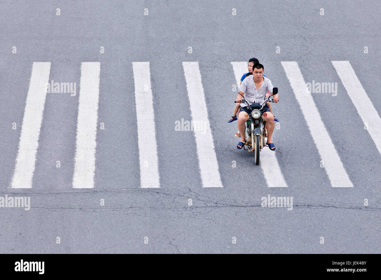 YANTAI-CHINA-JULY 18. Man on motorcycle crossing zebra path. Chinese motorcycle market is shrinking because of the ban on motorcycles. Stock Photo