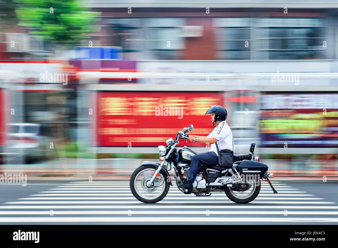 YANTAI-CHINA-JULY 22. Chinese man on a Suzuki motorcycle. The Chinese motorcycle market is shrinking because of the ‘ban on motorcycles. Stock Photo