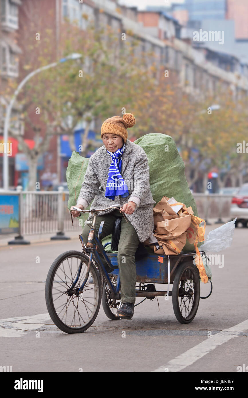 YIWU-CHINA-JAN. 8, 2016. Old woman transports recyclable stuff. Chinese cities grow at unprecedented speed, the amount of waste become a huge problem. Stock Photo