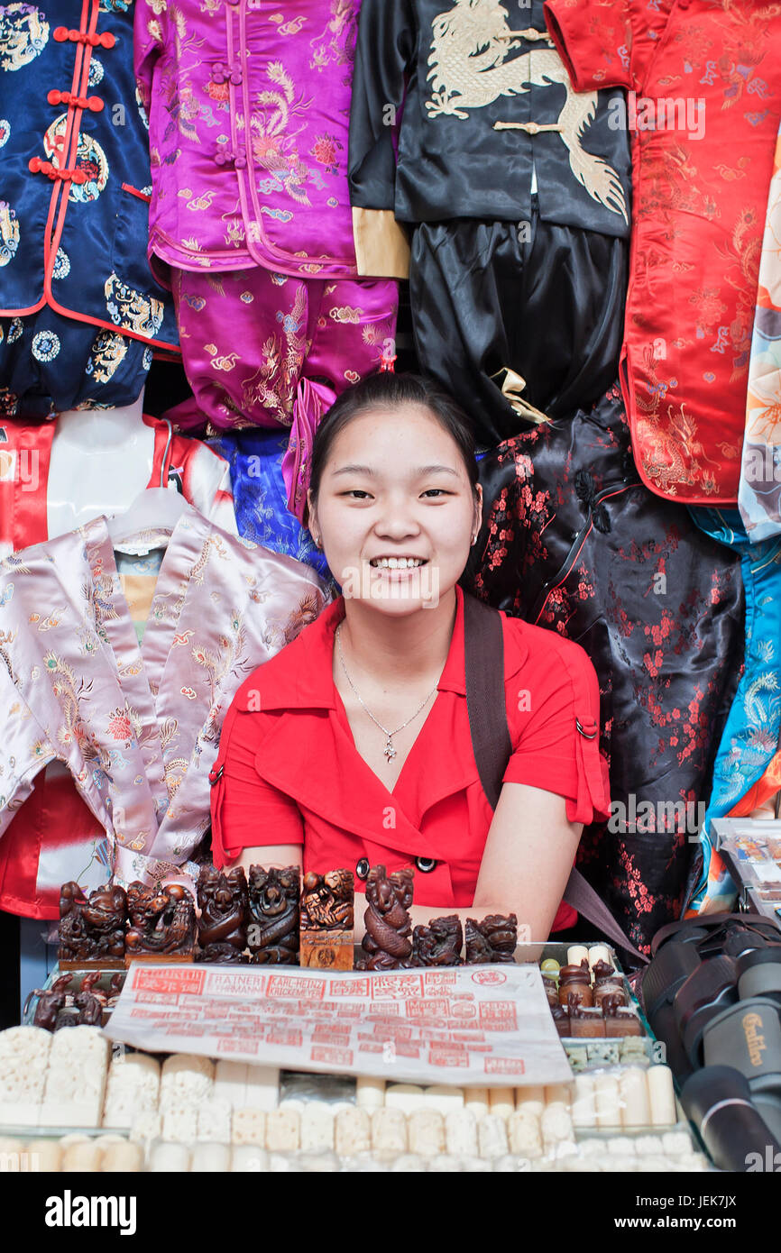 BEIJING-JULY 6. Girl in a stall with vendible on Panjiayuan Market. This market (48,500 sq. meter) is the biggest antique market in Asia. Stock Photo