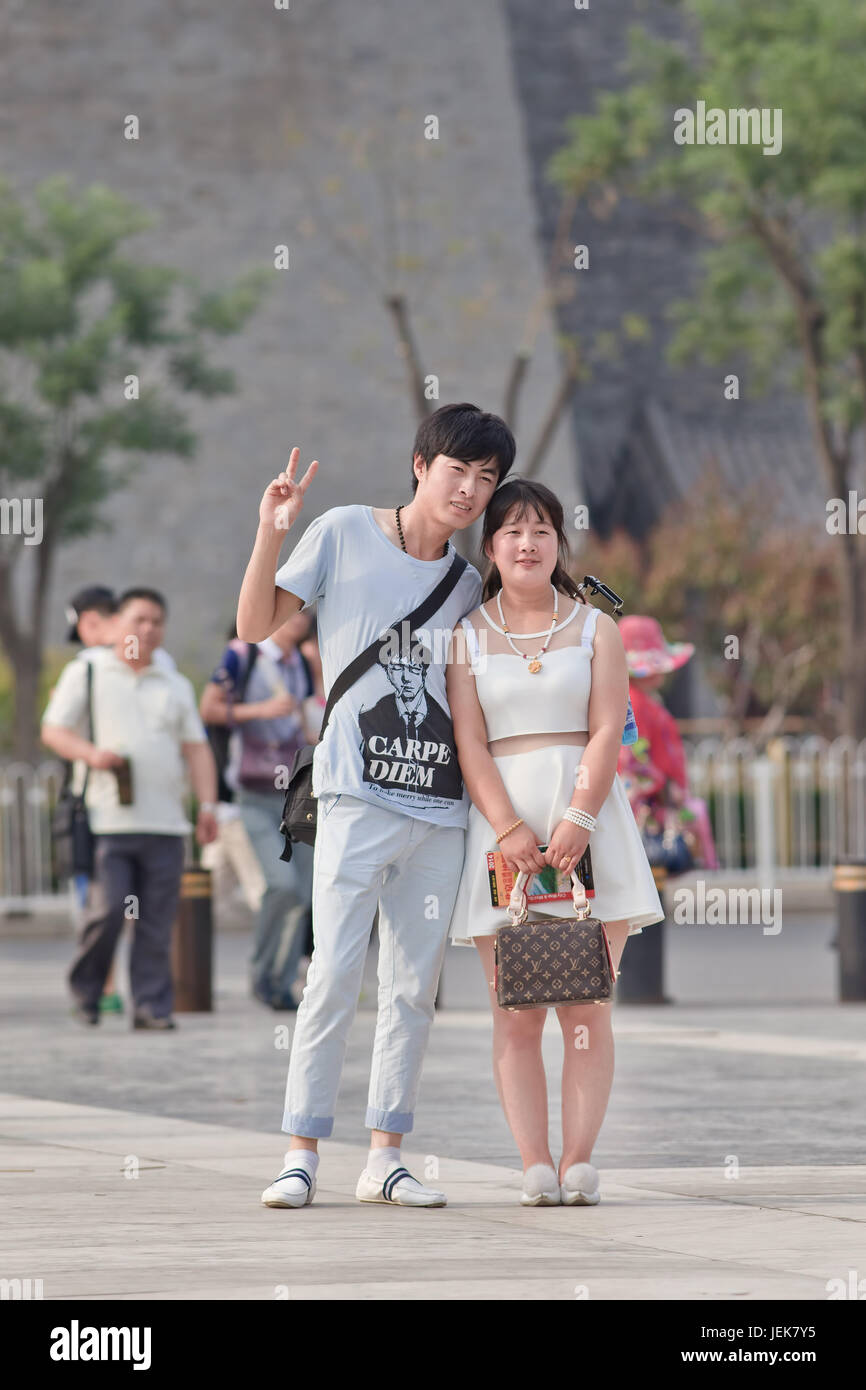 BEIJING-JUNE 9, 2015. Young couple pose for a photo on a summer day in Beijing city center with ancient watchtower on the background. Stock Photo