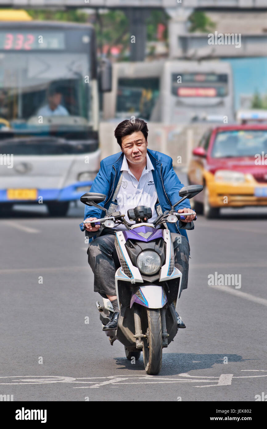 BEIJING-APRIL 28, 2016. Man on e-bike in city center. Many electric bikes in China are the scooter style e-bike that may or may not have pedals. Stock Photo