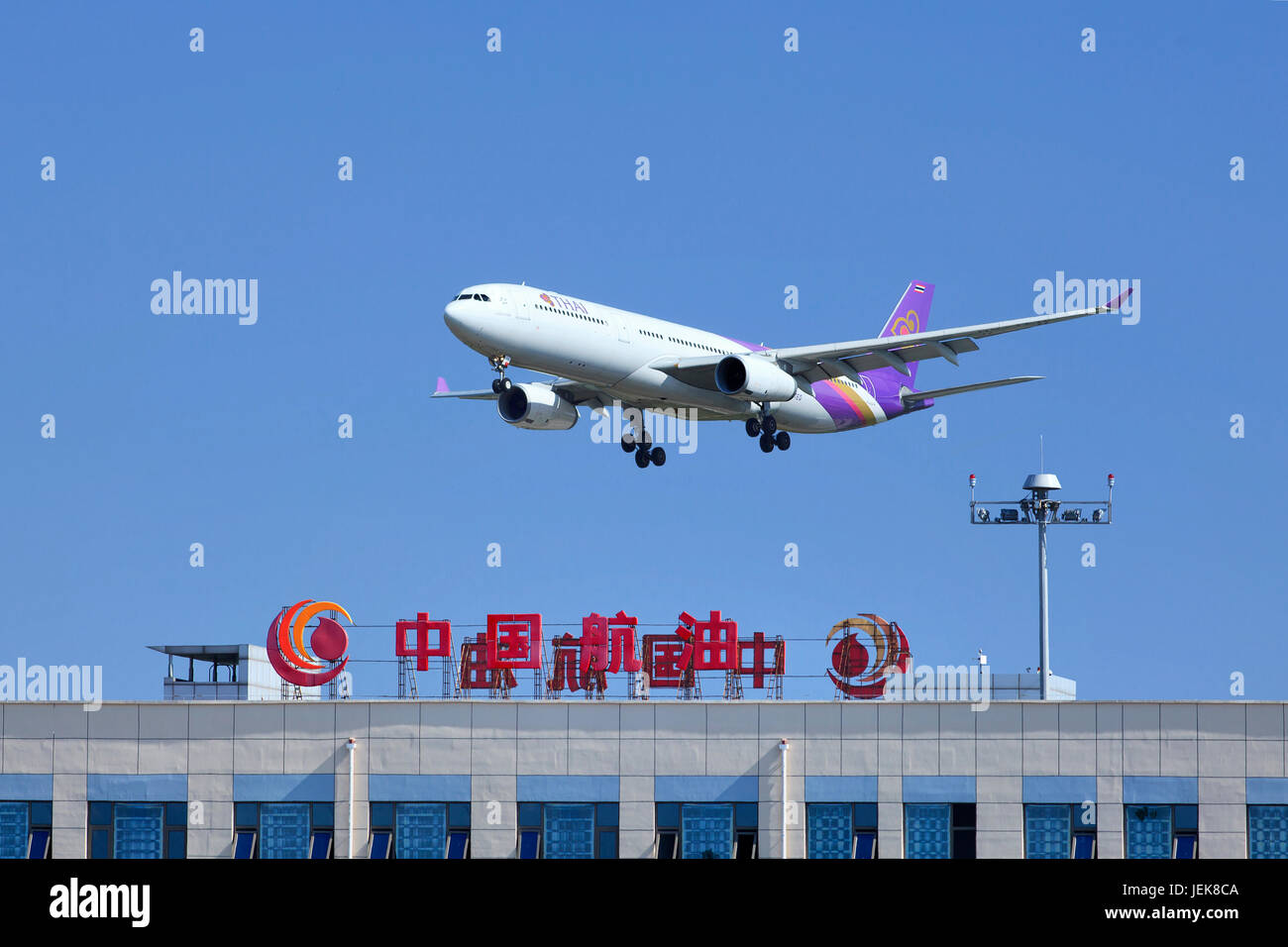 BEIJING-JULY 5. Thai Airways Airbus 330-343X skims over a building of China Aviation Oil Corporation. It is a wide-body twin-engine jet airliner. Stock Photo
