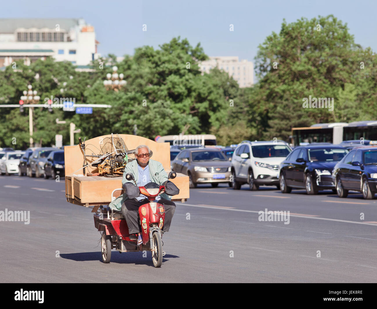 BEIJING-MAY 29, 2013. Chinese elderly transports a cabinet and folding bicycle on his electric bike. Stock Photo