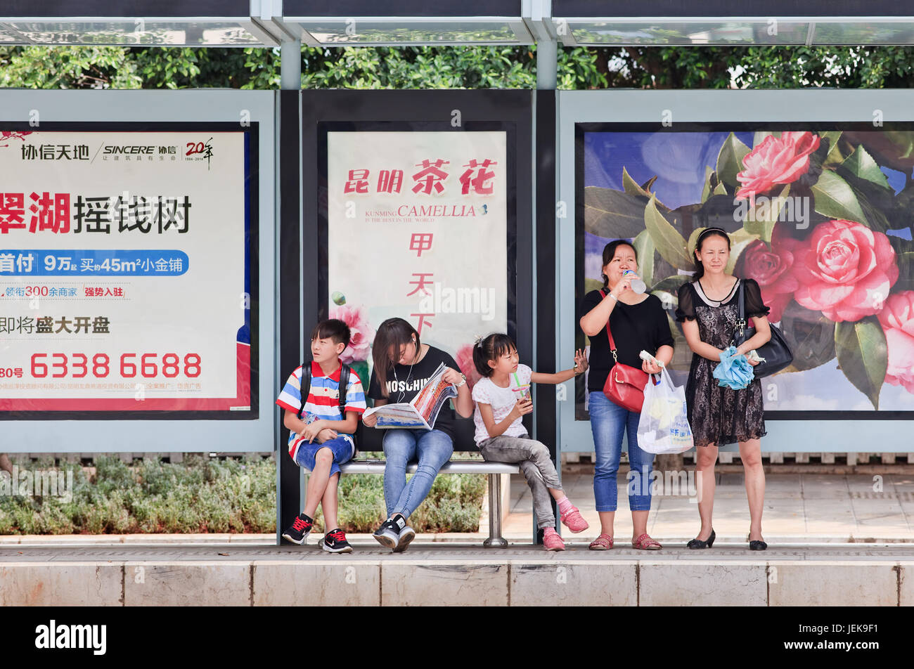 KUNMING-JULY 5, 2014. People at bus stop with advert. China’s outdoor advertising market grows annually more than 23% since 2000. Stock Photo