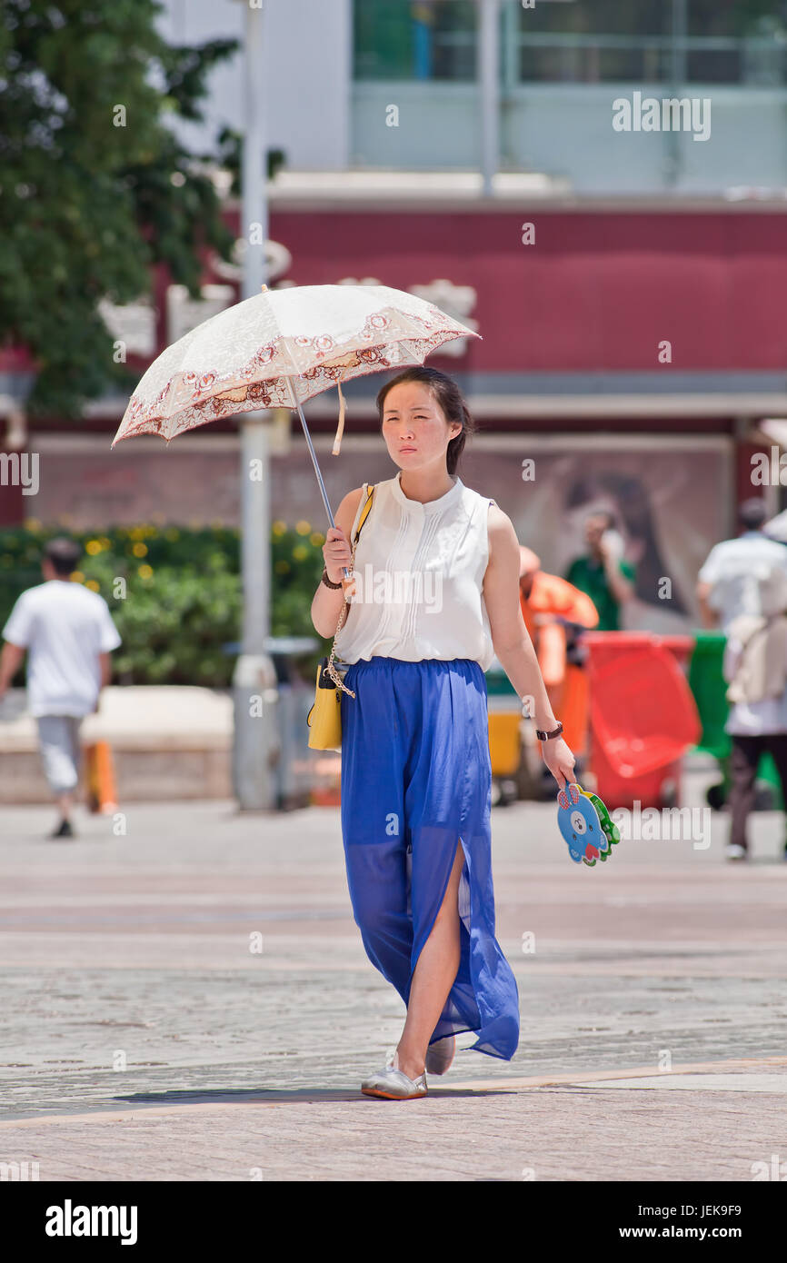 KUNMING-JULY 10, 2014. Pretty Chinese girl with umbrella as sun blocker. Since ancient times a pale skin is an absolute Chinese beauty ideal. Stock Photo