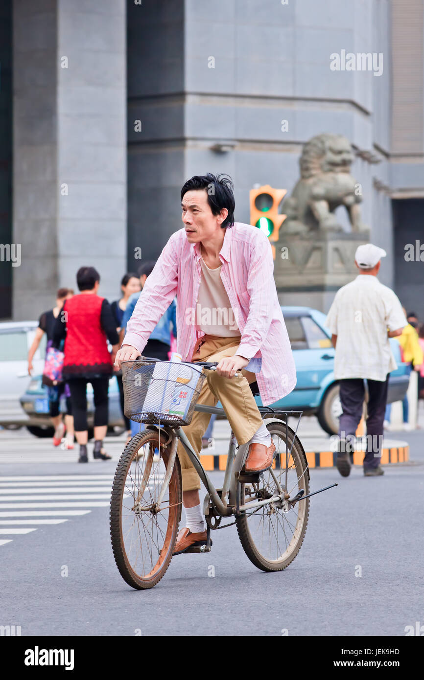 KUNMING-JUNE 30, 2014. Middle aged man cycles in city center. China has a population of 1,342,700,000, 500,000,000 bicycles and 37.2 cyclists. Stock Photo