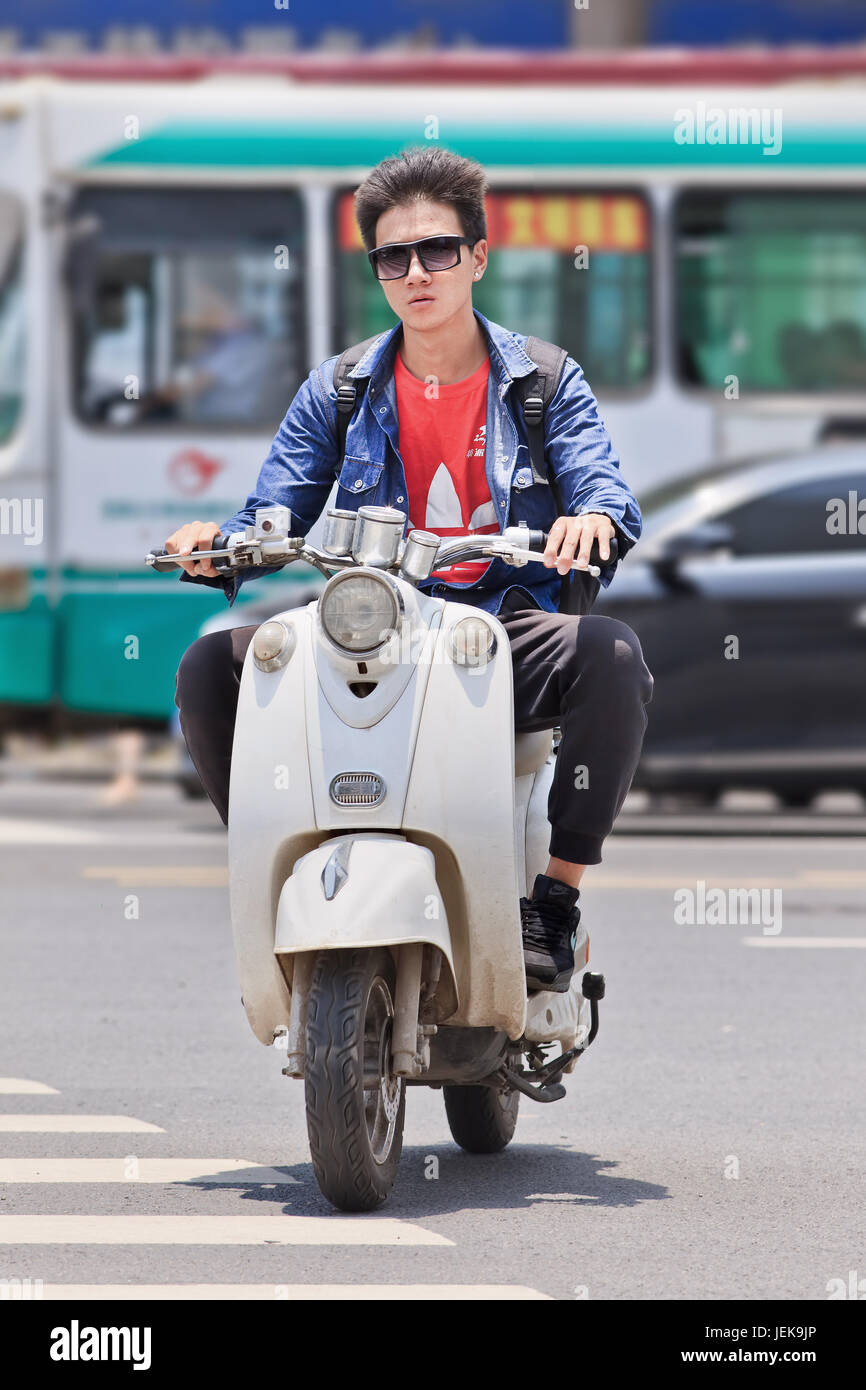 KUNMING-JULY 5, 2014. Cool guy on an e-bike. A lot of the electric bikes in China are the scooter style e-bike that may or may not have pedals. Stock Photo