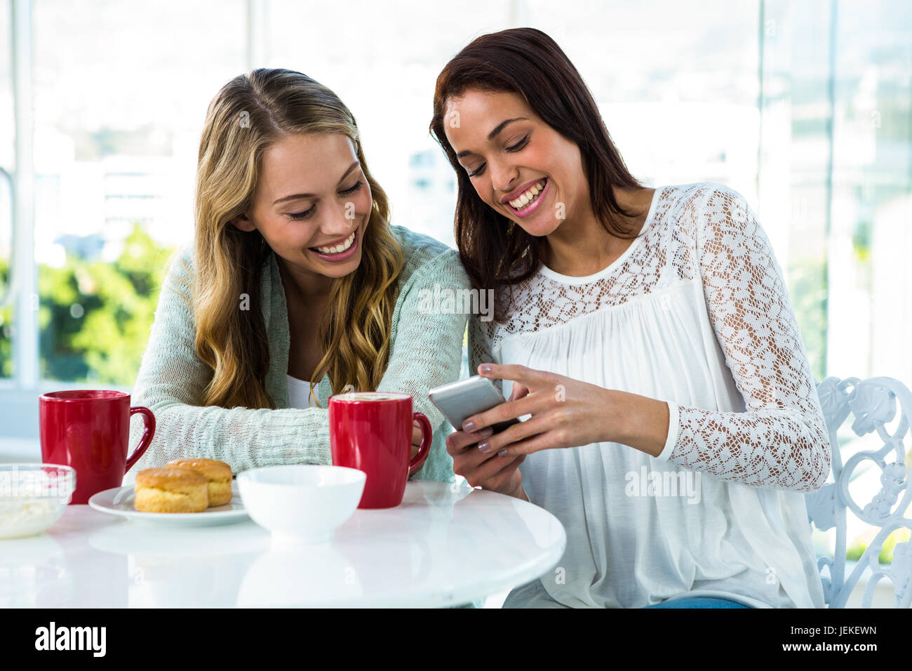 two girls watch a phone Stock Photo - Alamy