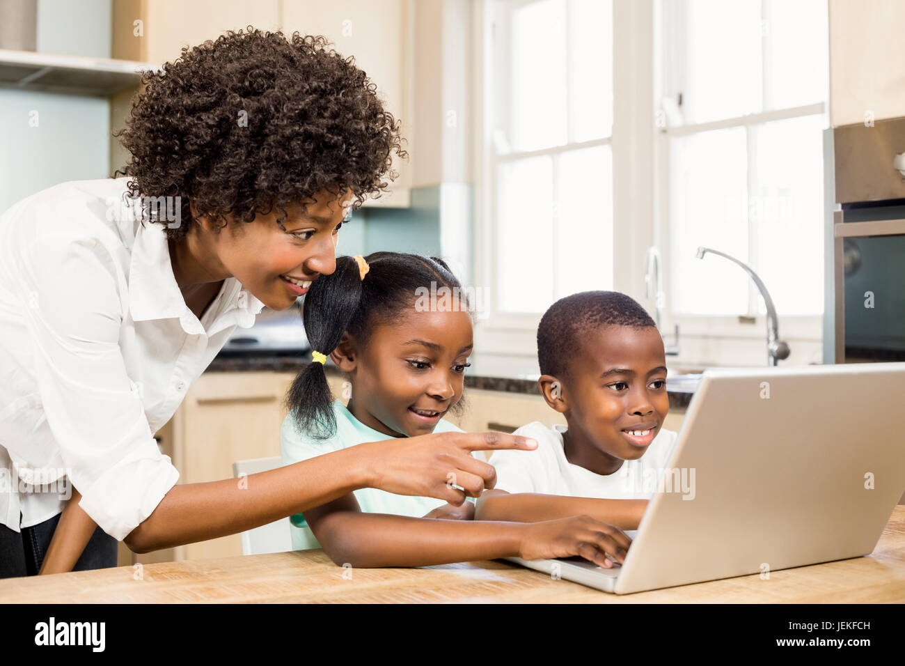 Happy family using laptop in the kitchen Stock Photo - Alamy