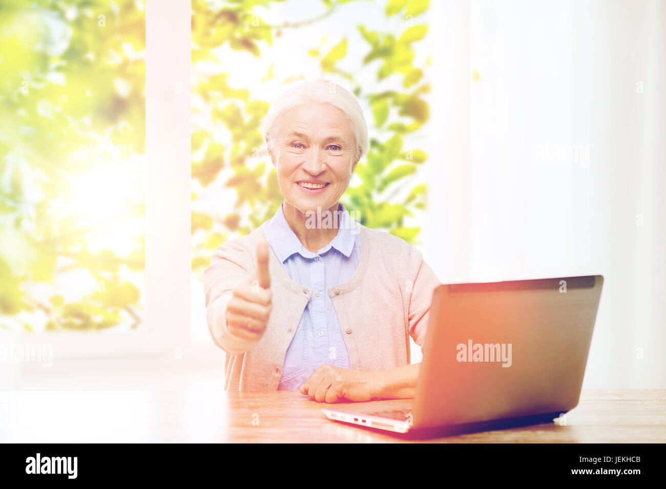 happy senior woman with laptop showing thumbs up Stock Photo - Alamy