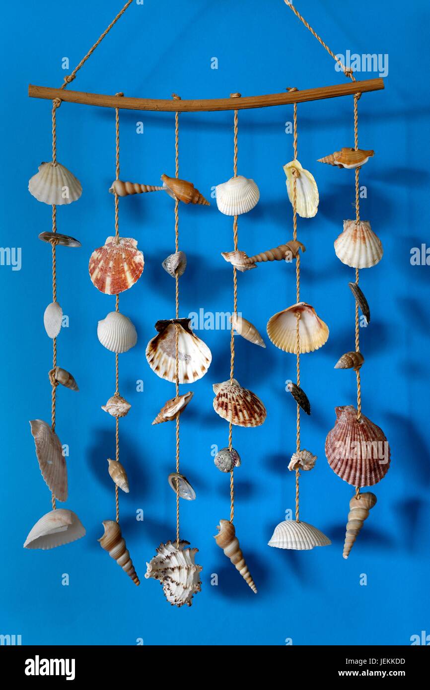 A wind chime with shells on a blue background on a stick Stock Photo