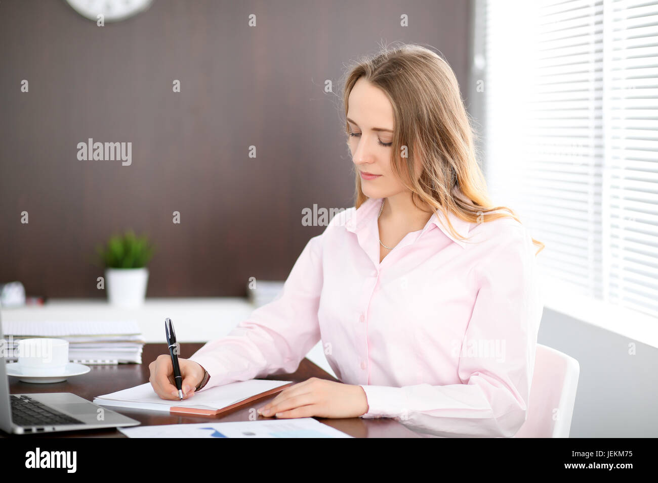Young business woman sitting at the table in the office Stock Photo - Alamy