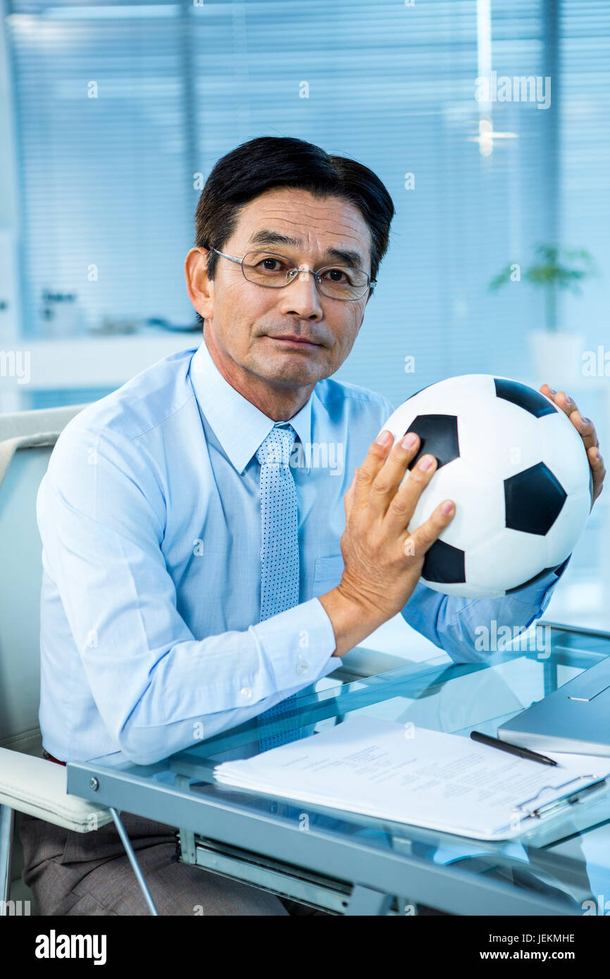 Asian businessman holding soccer ball Stock Photo - Alamy