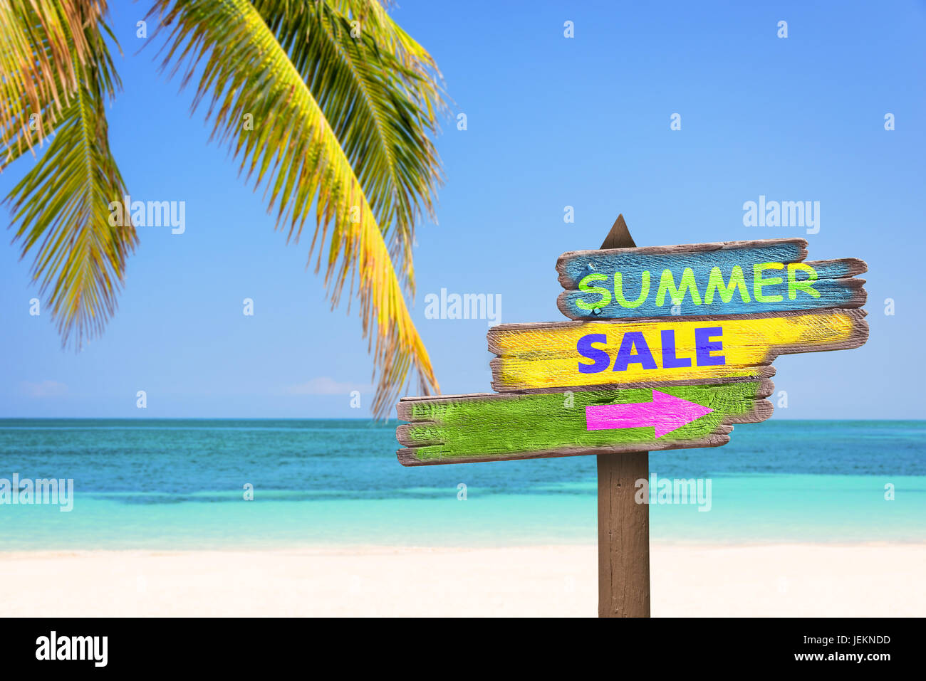 Summer sale written on pastel colored wooden direction signs, beach and palm tree background Stock Photo