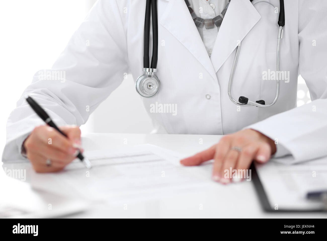 Close-up of a female doctor filling out application form , sitting at ...