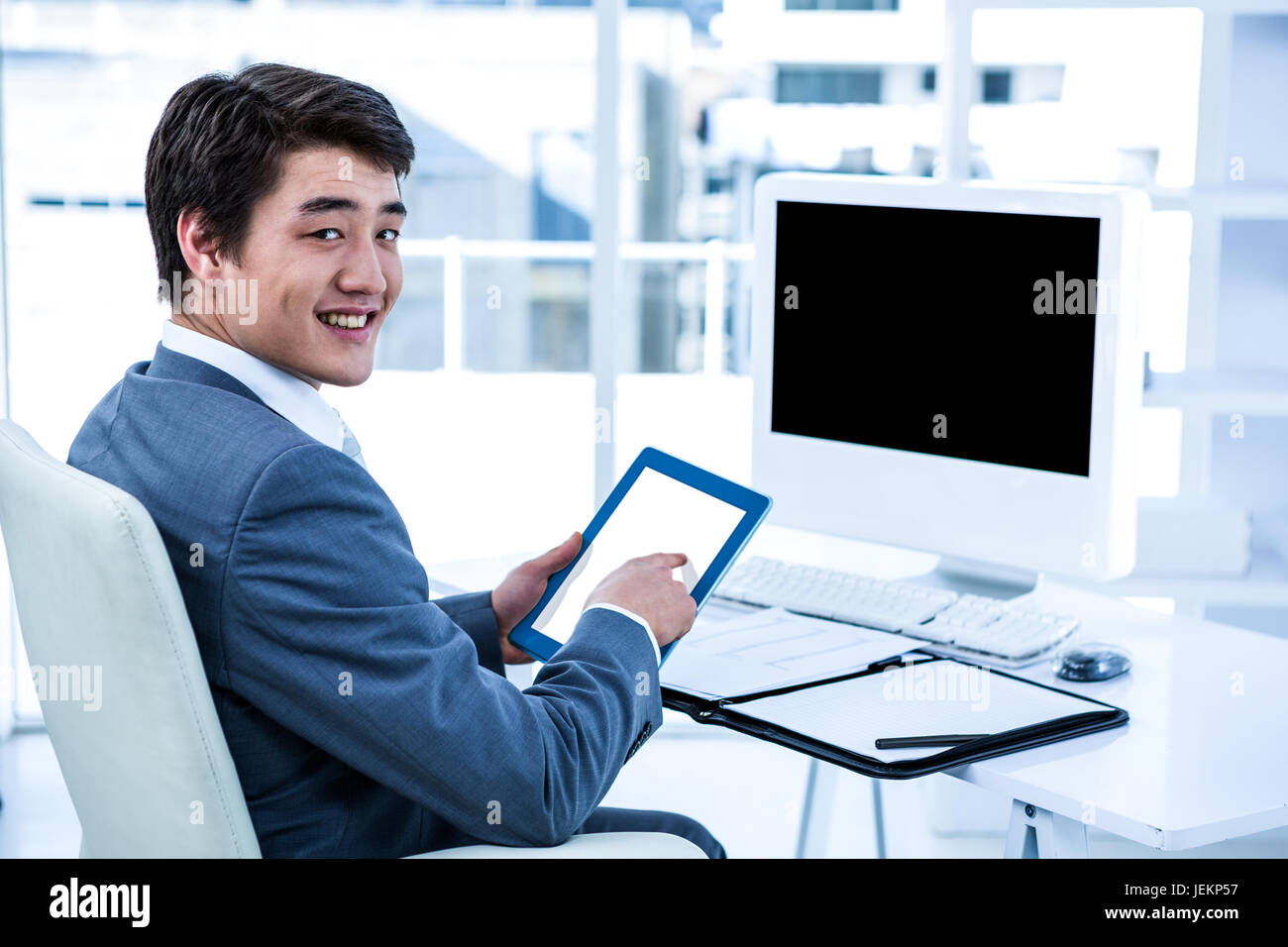 Smiling businessman using his tablet Stock Photo - Alamy